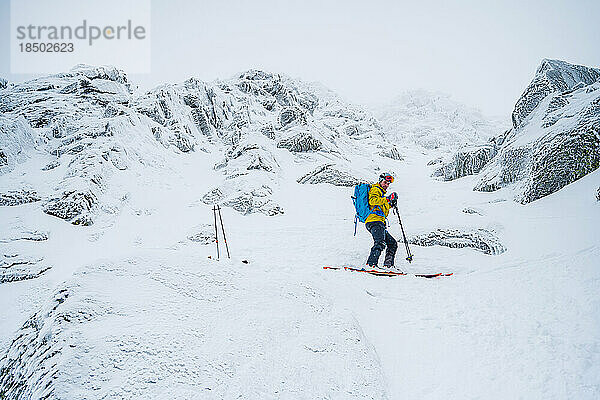 Skifahrer in gelber Jacke bereitet sich auf das Skifahren bei Frost vor