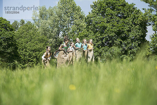 Gruppe von Mädchen spielen beim Sackhüpfen auf einem Feld  München  Bayern  Deutschland