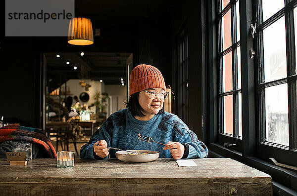 Lächelnde asiatische Frau beim Mittagessen in einem Café