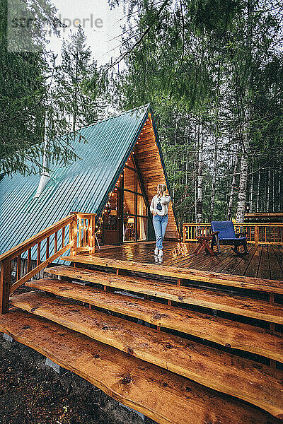 Mädchen auf einer Terrasse mit schöner Hütte im Wald