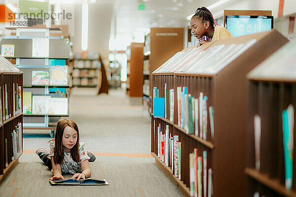 Mädchen beobachtet Freund beim Lesen in der Bibliothek