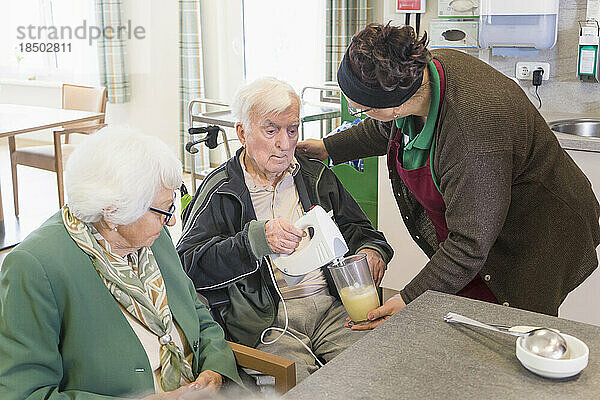Krankenschwester bereitet Essen mit älterem Mann im Pflegeheim zu