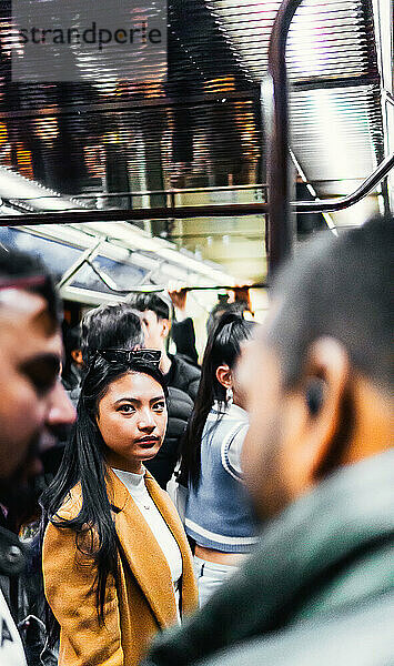 Asiatisches Mädchen in der U-Bahn  umgeben von Menschen