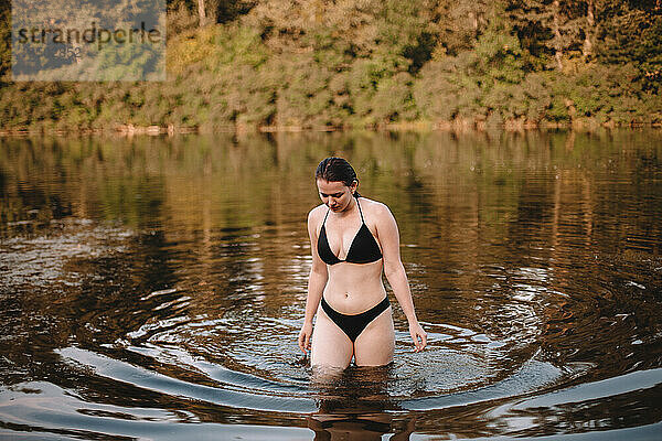 Junge Frau im Bikini spaziert im See