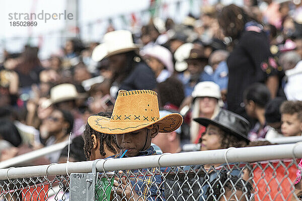Ein junger Cowboy nippt in der Menge beim AZ Black Rodeo an einem Strohhalm