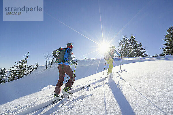 Skifahrer erklimmen den Schneeberg gegen den Himmel