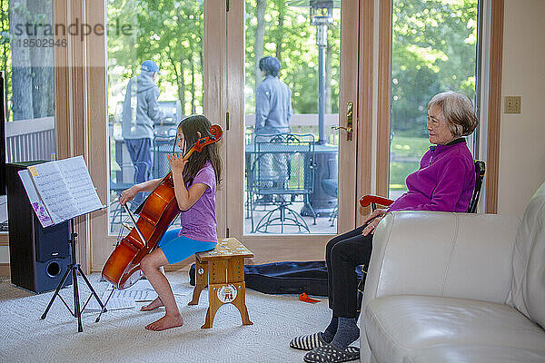 Ein kleines Mädchen gibt der Großmutter drinnen ein Cellokonzert