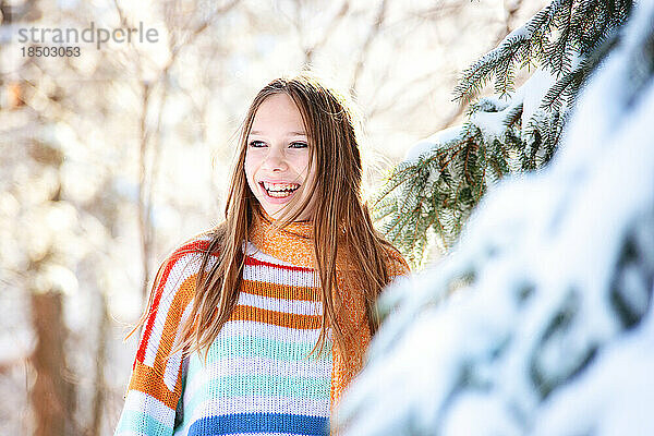 Schönes glückliches Tween-Mädchen mit blonden Haaren im Schnee.