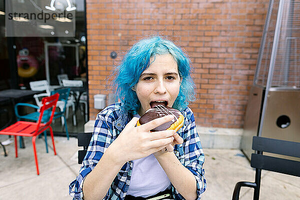 Teenager-Mädchen mit blauen Haaren will gerade einen Donut beißen