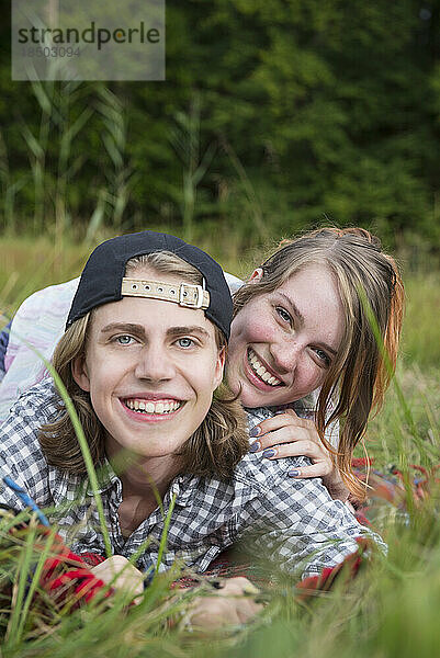 Porträt eines jungen Paares  das auf einer Wiese liegt und lächelt  Bayern  Deutschland