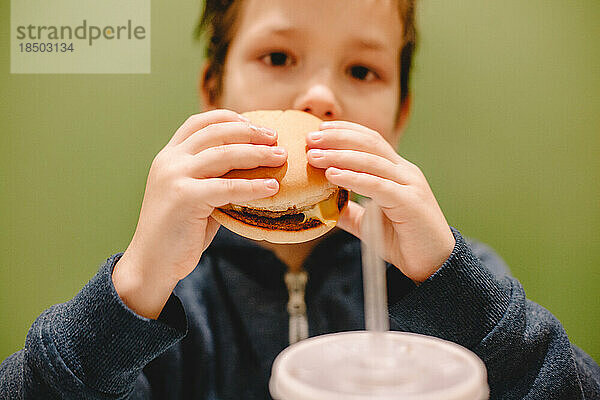 Junge isst Burger im Restaurant