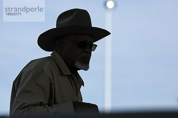 A cowboy silhouetted against an overcast sky at the AZ Black Rodeo