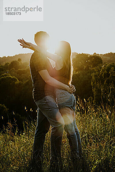 Mann und Frau umarmen sich im Sommer im Park vor der Sonne