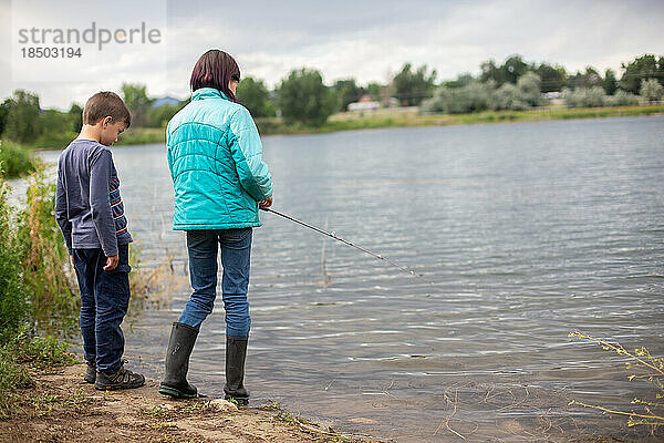 Geschwister angeln im Teich und schauen aufs Wasser