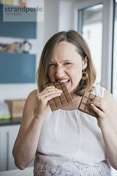 Porträt einer schwangeren Frau  die in der Küche Schokolade isst  München  Bayern  Deutschland