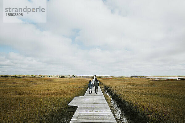 Zwei Jungen gehen auf der Promenade über die Salzwiese