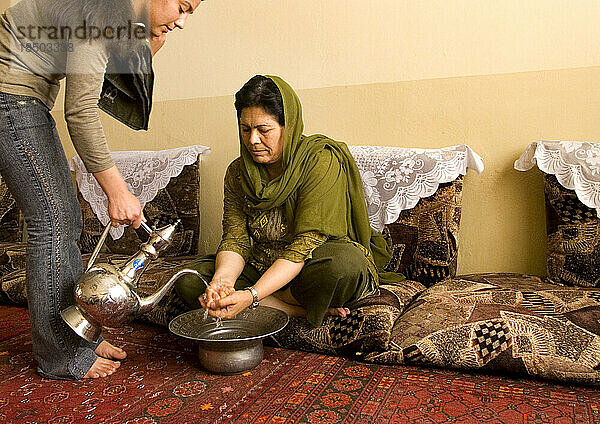 Frau in Kabul wäscht sich vor dem Essen die Hände mit Krug und Schüssel.