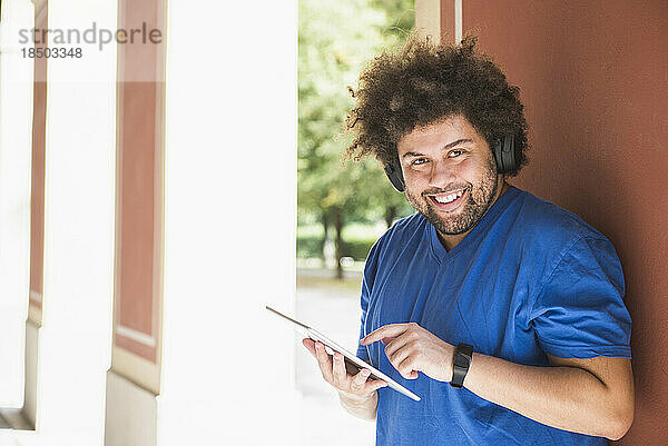 Junger Mann nutzt digitales Tablet und Kopfhörer im Freien