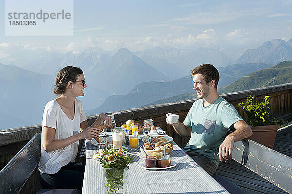 Junges Paar beim Frühstück auf der Terrasse und lächelnd  Zillertal  Tirol  Österreich