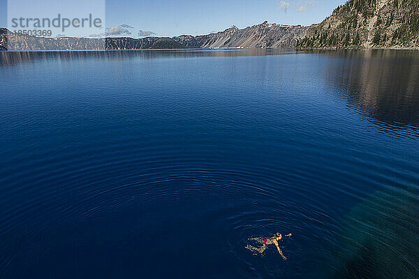 Eine junge Frau schwimmt im kalten  klaren Wasser des Crater Lake.
