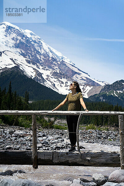 Abenteuerliche Frau auf der Holzbrücke mit Berg im Hintergrund
