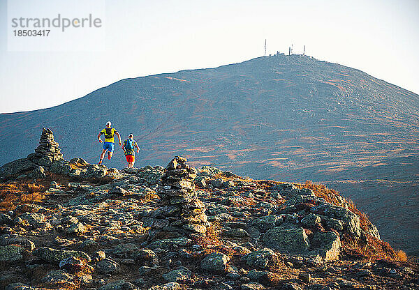 Männliche Trailrunner laufen bei Sonnenaufgang in den Bergen den Trail entlang