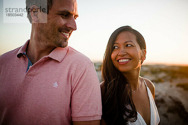 Mann und Frau lächeln einander am Strand in San Diego an