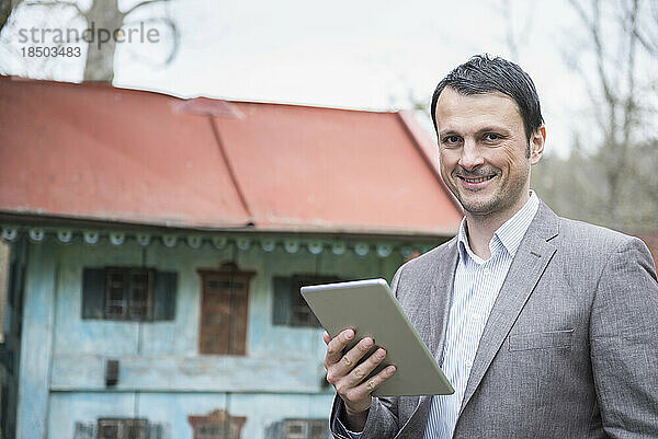 Porträt eines reifen Geschäftsmannes  der draußen ein digitales Tablet nutzt und lächelt  Bayern  Deutschland