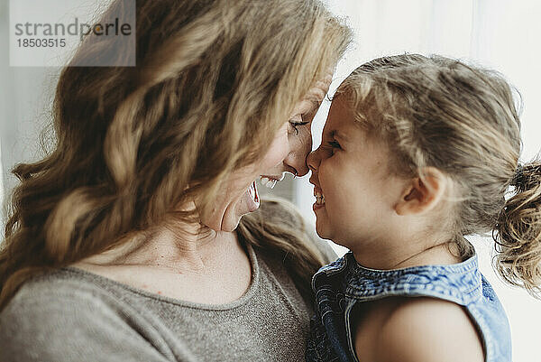 Close up view of mother and daughter touching noses in studio
