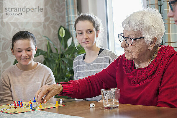 Mädchen spielen Ludo-Brettspiel mit älteren Frauen im Pflegeheim