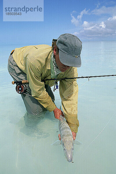Ein Salzwasser-Fliegenfischer hält einen Trophäen-Grätenfisch.