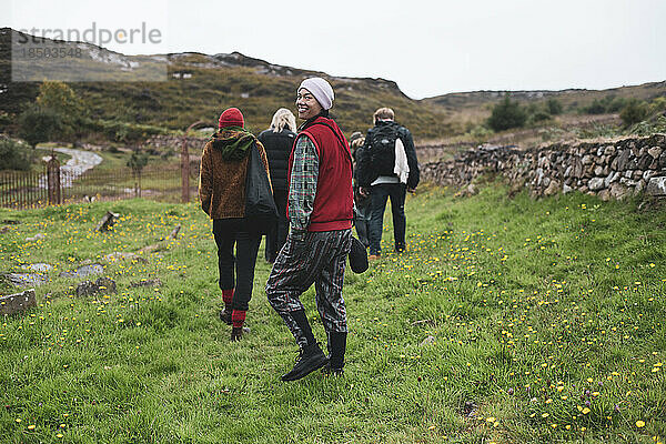 Eine Gruppe von Wanderern lächelt  während sie durch das Stone Village in Schottland spazieren