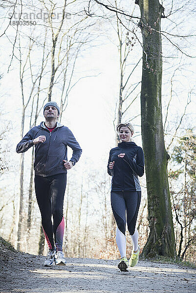 Mann und Frau joggen auf Fitnessparcours im Wald