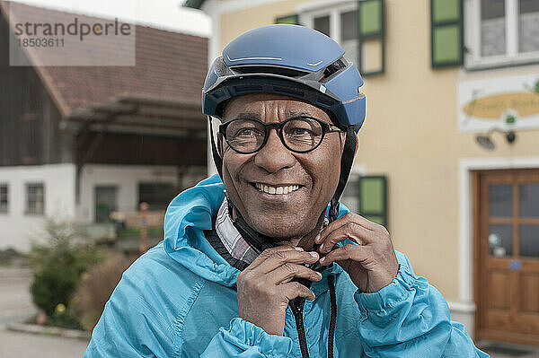 Älterer Mann  der seinen Fahrradhelm aufsetzt und lächelt  Bayern  Deutschland
