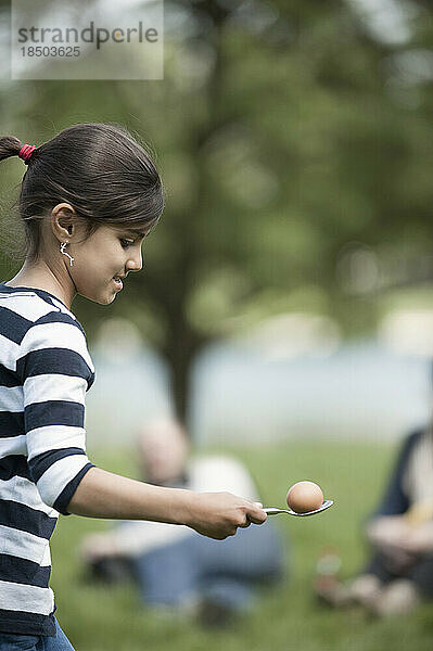 Mädchen balanciert ein Ei auf einem Löffel im Park  München  Bayern  Deutschland