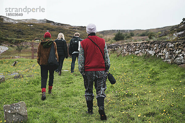 Eine Gruppe von Wanderern spaziert durch alte Ruinen auf einer abgelegenen Insel in Schottland
