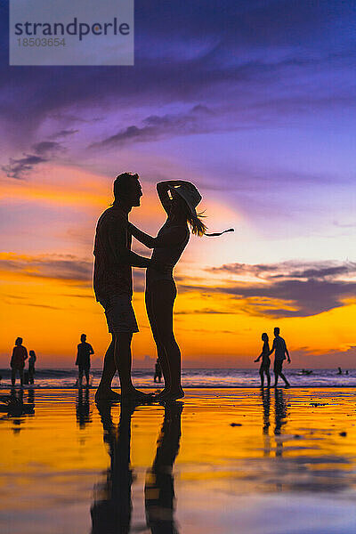 Junges Paar vergnügt sich am Meeresstrand. Sonnenuntergang auf Bali.