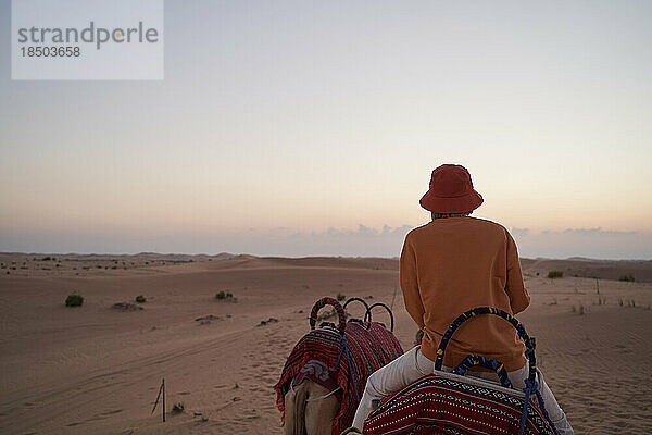 Touristin reitet während einer Safari auf einem Kamel in der Wüste.