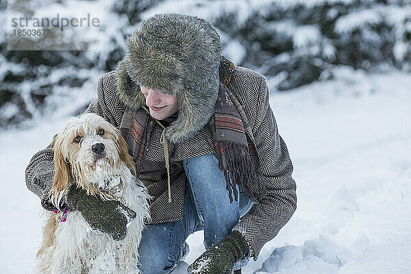 Junger Mann mit Hund in verschneiter Landschaft im Winter  Bayern  Deutschland