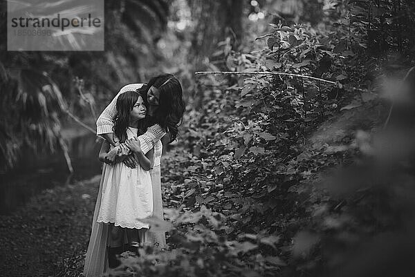 Mutter und Tochter umarmen sich und schauen sich im Wald an