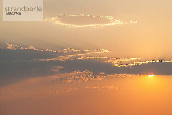 Die Sonne ragt vor Sonnenuntergang hinter der Wolke hervor