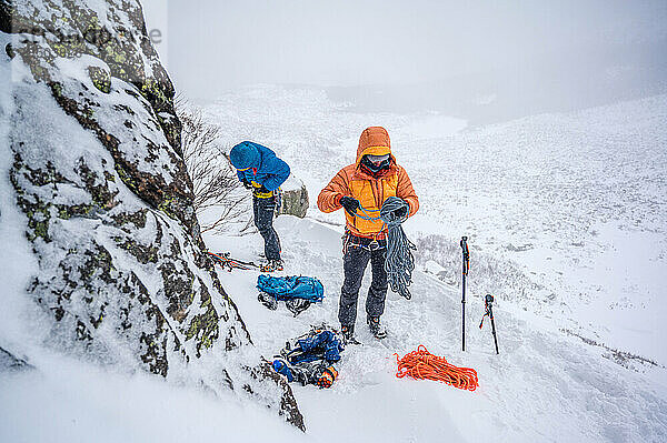 Männer bereiten ihre Ausrüstung für das Skitourengehen im Winter in einer Puffjacke vor