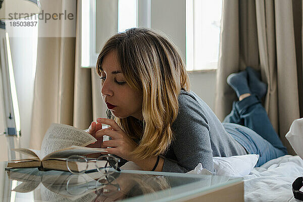 Junge Frau liest ein Buch in ihrem Zimmer