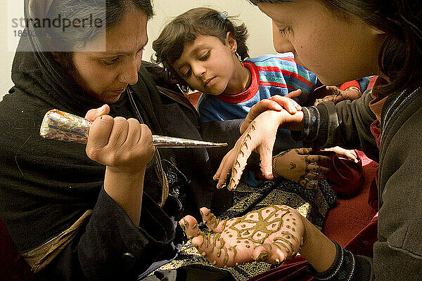 Eine Frau trägt in Kabul Henna auf die Hände ihrer Töchter auf.