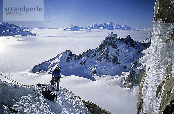 Ein Bergsteiger klettert auf einen Bergrücken an der Nordwestwand des Cerro Torre mit dem Cerro Rincon  dem Vulkan Lautaro und dem kontinentalen Inlandeis