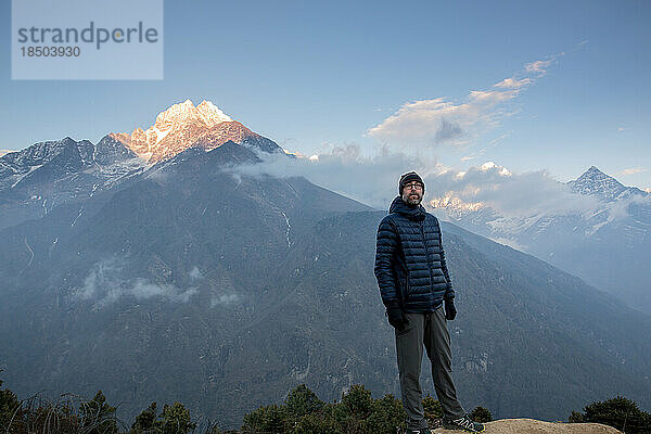 Ein Mann blickt im Abendlicht auf einem Berg auf den Himalaya.