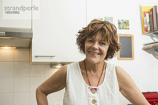 Porträt einer älteren Frau  die in der Küche steht und lächelt  München  Bayern  Deutschland