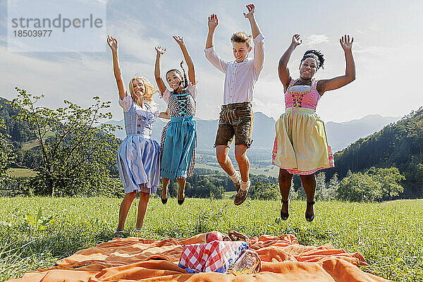 Teenager-Freunde springen vor Freude beim Picknick  Bayern  Deutschland