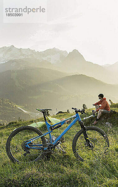 Mountainbiker machen eine Pause und bewundern die malerische Aussicht auf die Berge  Bayern  Deutschland