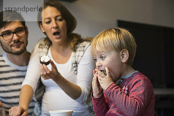 Kleiner Junge isst Dessert mit weit geöffnetem Mund  während die Eltern schockiert sind  München  Deutschland